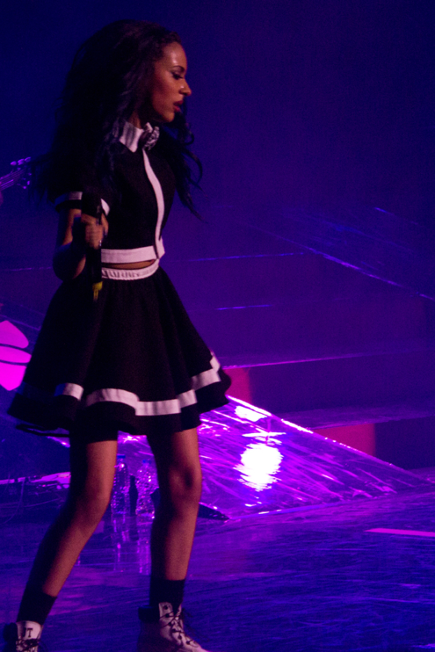 Eine Frau in einem schwarzen Kleid hält ein Mikrofon, während sie tanzt.