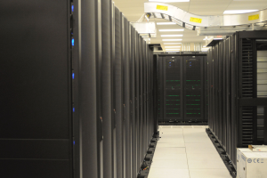 Ein Datenzentrum mit einer Reihe von Servern, beleuchtet von Deckenlampen, ordentlich und gut beleuchtet.