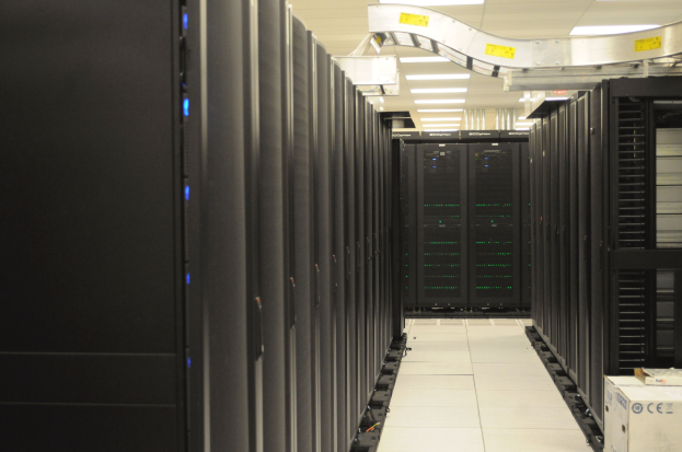 Ein Datenzentrum mit einer Reihe von Servern, beleuchtet von Deckenlampen, ordentlich und gut beleuchtet.