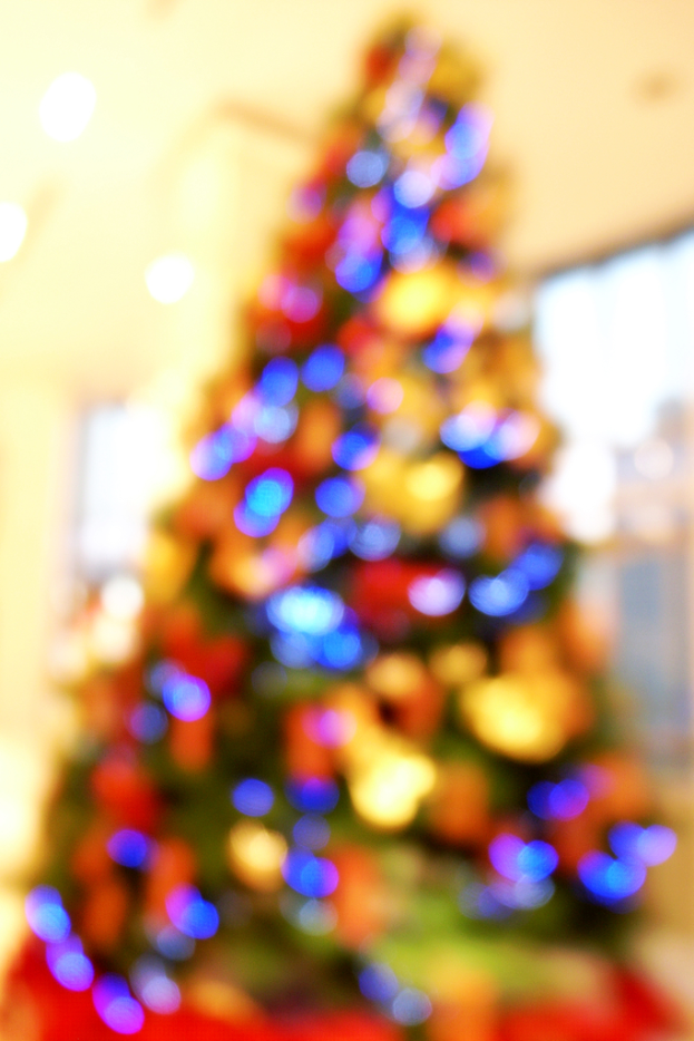 Eine unscharfe Innenaufnahme mit einem Weihnachtsbaum in der Mitte, der mit Lichtern und Dekorationen geschmückt ist.