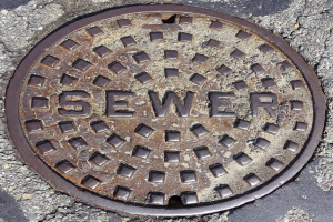 Ein Metall-Schachtoblenden auf dem Boden mit dem Wort 'Kanalisation' darauf.