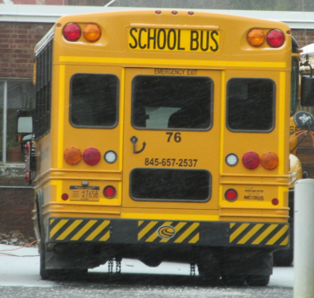 Ein gelber Schulbus mit der Aufschrift ''Schulbus'' vor einem Backsteingebäude mit Fenstern.