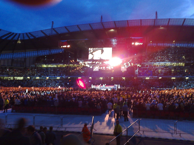 Ein Konzertsaal mit Menschen, Scheinwerfern und einer Projektionsleinwand.