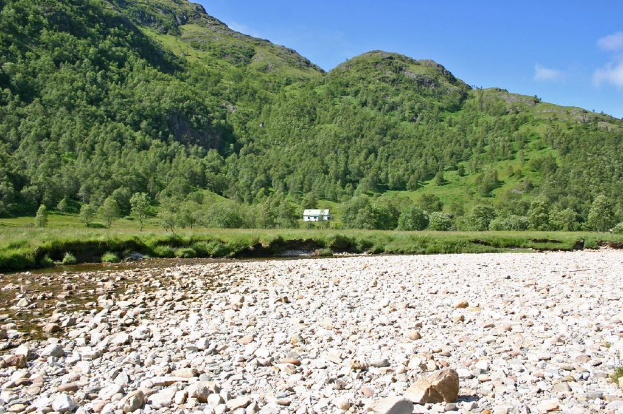 Hügel in der Mitte, Felsen und eine Hütte unten und Himmel oben.