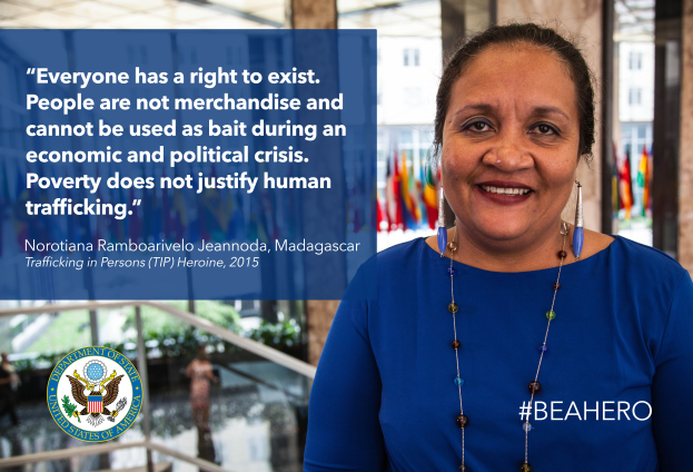 Eine Frau in einem blauen Kleid steht lachend vor einem Gebäude mit einer Aussage über Menschenrechte, umgeben von Menschen, Pflanzen und Flaggen, und einem Logo und Text auf der linken Seite.