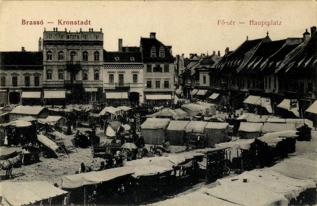Ein Schwarz-Weiß-Foto eines belebten Marktes in Kronstadt, Deutschland, mit Menschen, Zelten und Gebäuden mit Fenstern im Hintergrund und Text auf dem Bild.