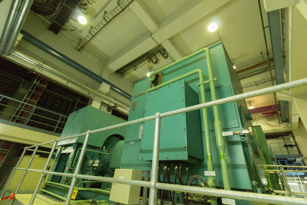 Ein großes industrielles Wärmetauschergerät in einem Gebäude, umgeben von Geländern, Rohren, Lampen und anderer Ausrüstung.