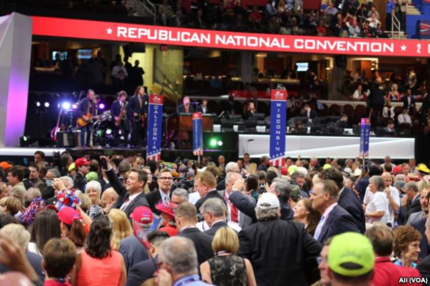 Eine große Menschenmenge steht vor einer Bühne mit Bannern, Stufen, Stühlen, Musikinstrumenten und Lichtern auf der Republican National Convention.