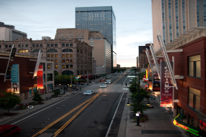 Eine Stadtansicht mit einer Straße, gesäumt von Gebäuden und Wolkenkratzern, unter dem Himmel.