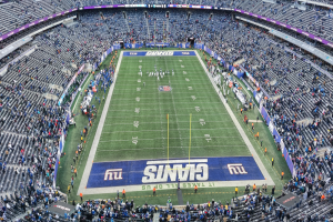 Ein fußballstadion voller Zuschauer, Spieler und diverser Gegenstände auf dem Feld, darunter Schilder mit Text und Sitzreihen.
