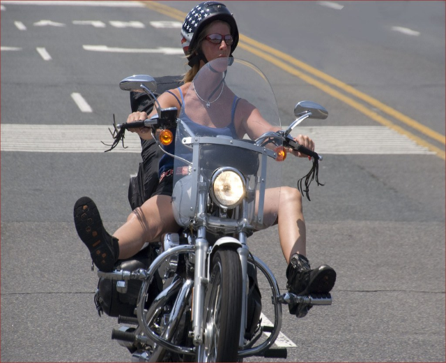 Eine Frau mit schwarzem Helm fährt ein Fahrrad auf einer Straße.