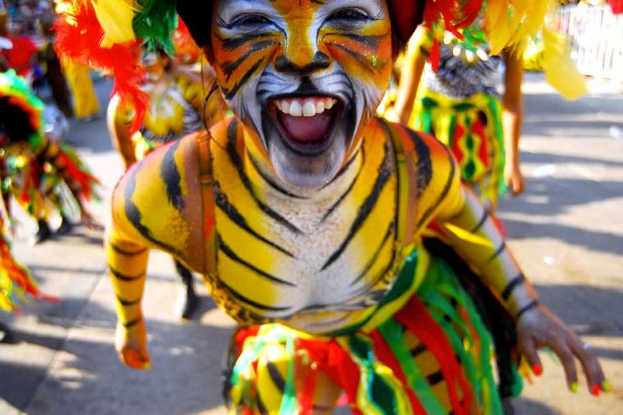 Eine Gruppe von Menschen in bunten Kostümen und Schminke, mit einer Frau in einem Tigerkostüm, bei einem Karneval.