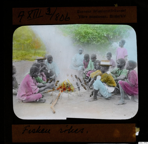 Gruppe von Kindern um ein Feuer sitzend, einige mit Hüten, mit Bäumen und Text im Hintergrund.