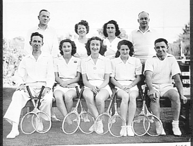 Schwarzes Foto einer Gruppe von Menschen auf einer Bank sitzend, die lächeln und Tennisrackets halten, mit Bäumen und einem klaren Himmel im Hintergrund und dem Text "Tennis Hall of Fame" unten.