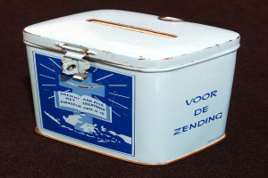 Weißer und blauer Blechspartopf mit einem blauen und weißen Schild, auf dem "Voor de Zending" steht, auf einer schwarzen Oberfläche.