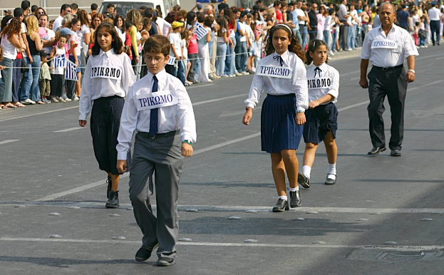 Eine Gruppe von Menschen, die auf einer Straße gehen und Abzeichen auf ihren Hemden tragen, mit einer großen Menge, die sich um die Straße sammelt.