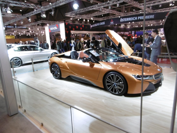 Ein schickes schwarzes BMW i8 Cabrio mit Chromakzenten auf der Internationalen Automobil-Ausstellung in Frankfurt umgeben von formell gekleideten Gästen in einer Atmosphäre der Aufregung.