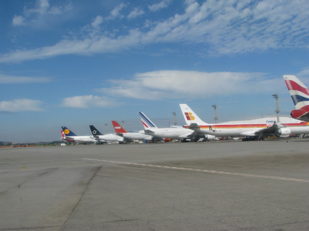Eine Start- und Landebahn mit einigen Flugzeugen, Pfählen, Kabeln und einer bewölkten Himmel