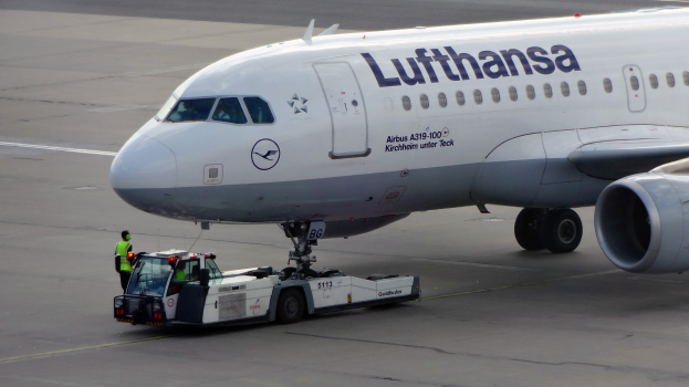Lufthansa Airbus A319-100 auf dem Frankfurter Flughafen-Rollfeld mit einem Bodenfahrzeug und einer Person in der Nähe, bereit zum Start.