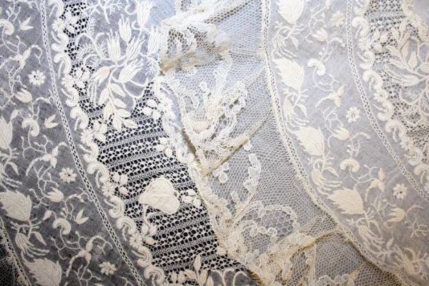 Nahaufnahme eines weißen Hochzeitskleids mit feiner Spitzenverzierung.