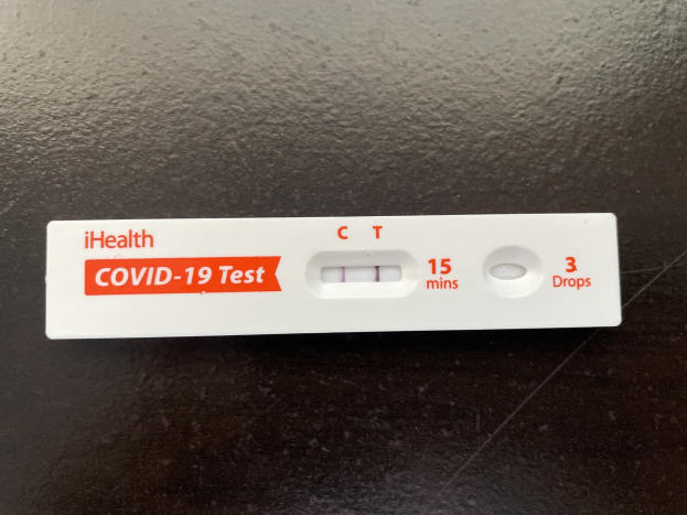 Eine schwarze Oberfl├Ąche mit einem weißen und roten Covid-19-Testthermometer, das Text und Zahlen anzeigt.
