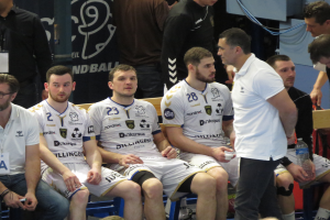 Eine Gruppe von Männern sitzt auf einer Bank, einige halten Flaschen, im Hintergrund ist eine Fahne mit der Aufschrift "Nordkraque vs Bordeaux."