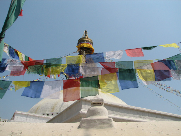 Ein weißer Grabstein, geschmückt mit zahlreichen bunten Fahnen.