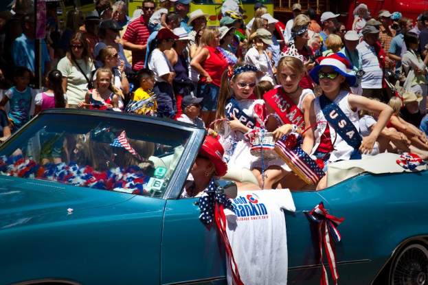 Eine Frau fährt ein Auto mit drei Mädchen darin, während Menschen im Hintergrund zusehen.