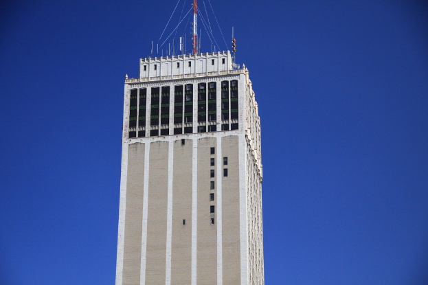 Ein hoher Turm mit Antennen und Signalmasten oben drauf, vor einem Himmel-Hintergrund.