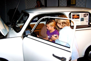 Zwei Kinder versuchen, in ein Auto mit anderen Menschen in der Nähe zu steigen.