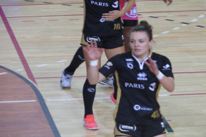 Eine Gruppe von Frauen in Sportkleidung beim Volleyballspielen auf einem Platz.
