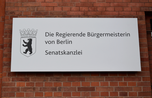 Ein Ziegelgebäude mit einer Tafel, auf der 'Berlin' steht, und einer Tafel mit Text und Logo an der Wand.