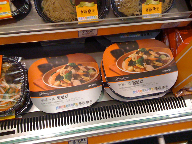 Lebensmittelboxen auf Regalen mit Preiszetteln.