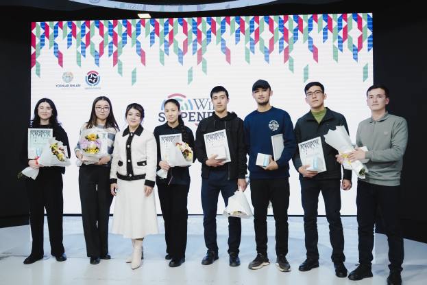 Eine Gruppe von Menschen auf einer Bühne mit Bücher und Blumensträußen, im Hintergrund ein Bildschirm mit der Aufschrift "Yogyakarta International School of Science and Technology".