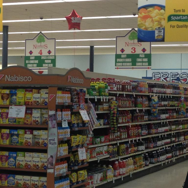 Ein Supermarkt-Innenraum mit sichtbaren Lebensmitteln, Deckenleuchten und Beschriftungen.