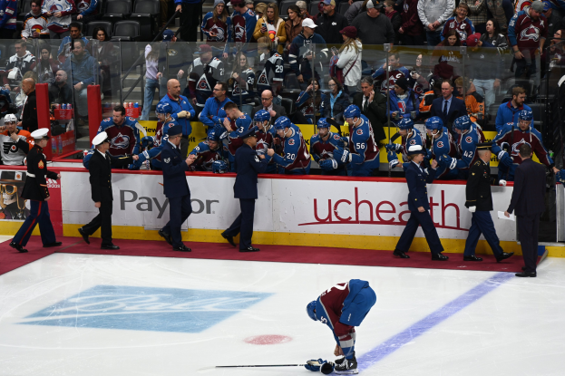 Eishockeyspieler auf dem Eis von Fans und Teammitgliedern umgeben während eines Spiels zwischen Colorado Avalanche und San Jose Sharks am 3/24/15.