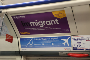 Ein Zug mit einer Tafel, auf der "Immigrant" steht, mit Plakaten an der Wand, einem Griff und einer Stange.