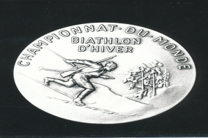 Eine Silbermedaille mit einer Abbildung eines Mannes, der Ski fährt, und einer Inschrift, vor einem schwarzen Hintergrund.