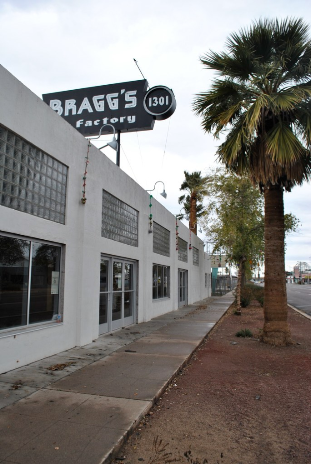 Ein Gebäude mit einer Flagge, auf der "Braggs Factory" steht, umgeben von Bäumen.