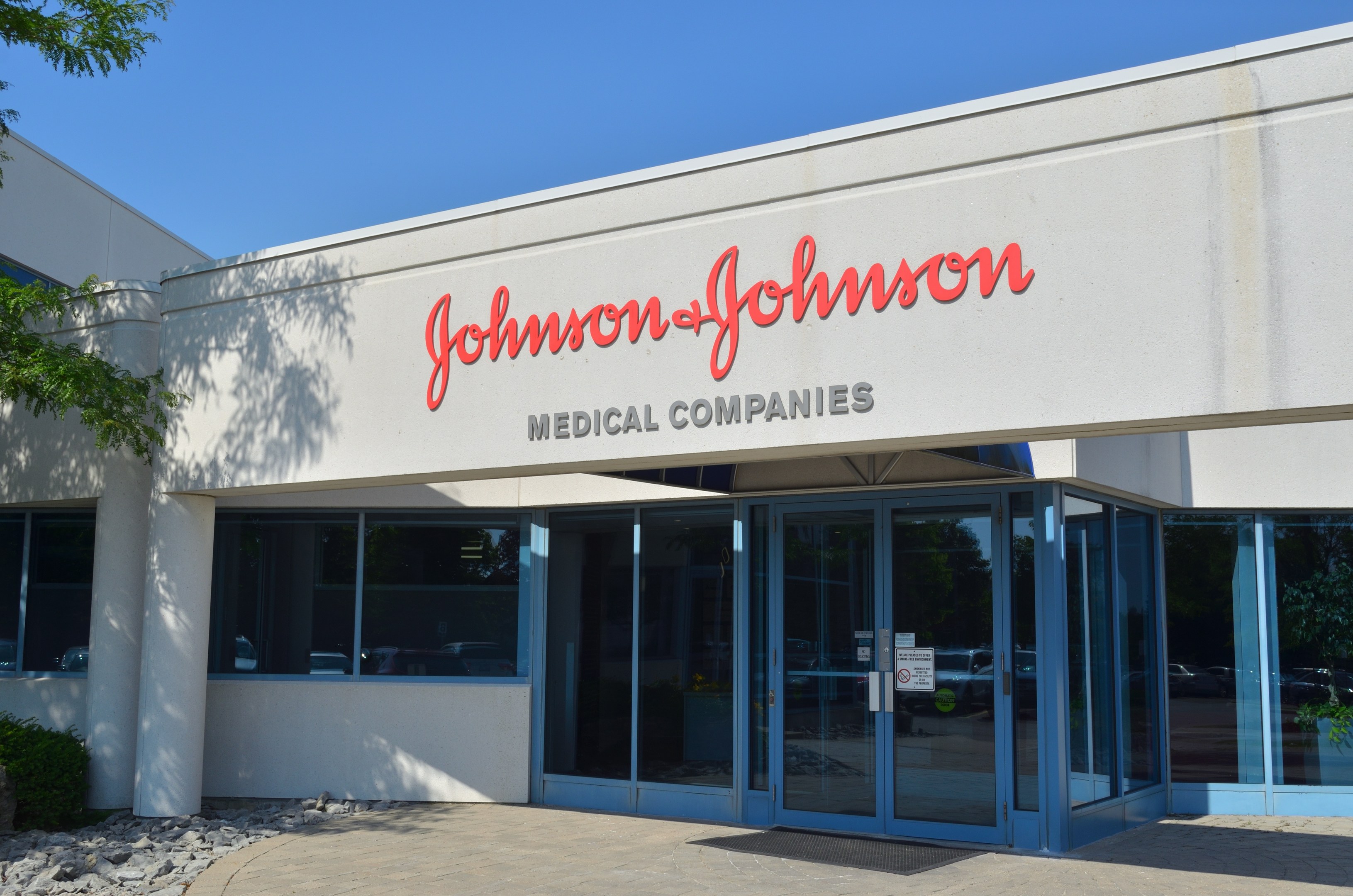 Außenansicht des Johnson & Johnson Medical Companies-Gebäudes mit Glaswänden, einem Baum auf der linken Seite und einem klaren blauen Himmel im Hintergrund.