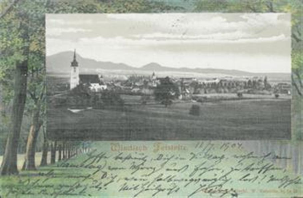 Eine alte Ansichtskarte, die eine Stadtansicht von einem Hügel aus zeigt, mit Bäumen, Gebäuden, fernen Hügeln und einem bewölkten Himmel, beschriftet mit "Wiesbaden, Deutschland" unten.