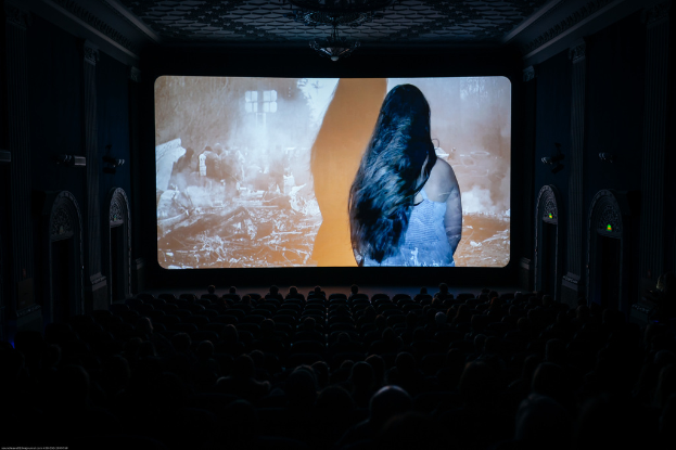 Eine Leinwand, die einer Theaterleinwand ähnelt, ist zentral in einer dunklen Umgebung positioniert.