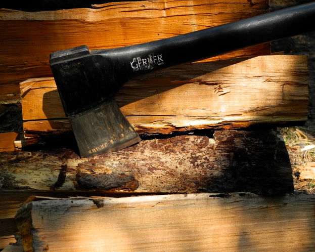 Ein schwarzes Beil und mehrere Holzstücke sind auf einer Oberfläche ausgelegt.