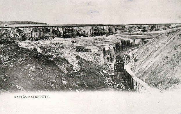 Ein altes Schwarz-Weiß-Foto eines Zuges, der in einen Tunnel einfährt, mit einer Brücke und Himmel im Hintergrund und Text unten, der "Kaflas Kalkbrott, das erste Bergwerk in Deutschland" lautet.