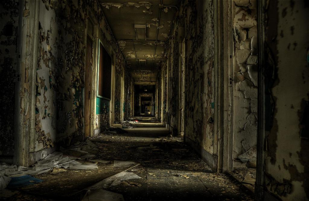 Ein altes Gebäude mit Papieren auf dem Boden und einer Tafel an der linken Wand.