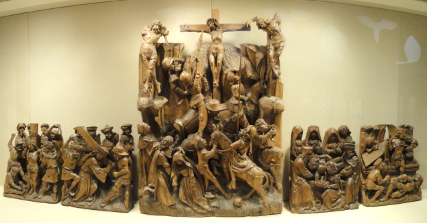 Eine Gruppe von Holzskulpturen, die zusammen in einem Museum ausgestellt sind, mit einer Wand im Hintergrund.