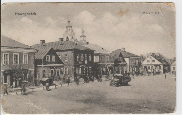 Schwarzes und weißes Foto einer Stadtstraße in Nowogrodziec, Deutschland, mit Gebäuden, Menschen, Karren, Pfählen, Bäumen und Himmel, mit der Beschriftung "Marktplatz in Nowogrodeek, Deutschland" oben und unten.