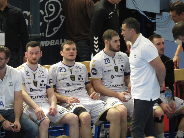 Eine Gruppe von Männern auf einer Bank sitzend, einige halten Flaschen, im Hintergrund ein Banner mit der Aufschrift "Nordkraque vs Bordeaux."